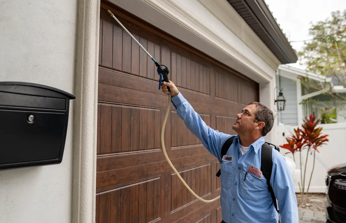 A Liberty Pest Management technician spraying the exterior of a Florida home